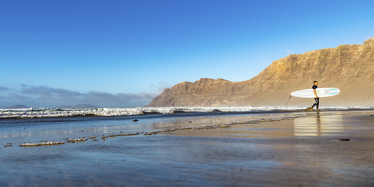 Surfista caminando por playa de Famara - Yaizart