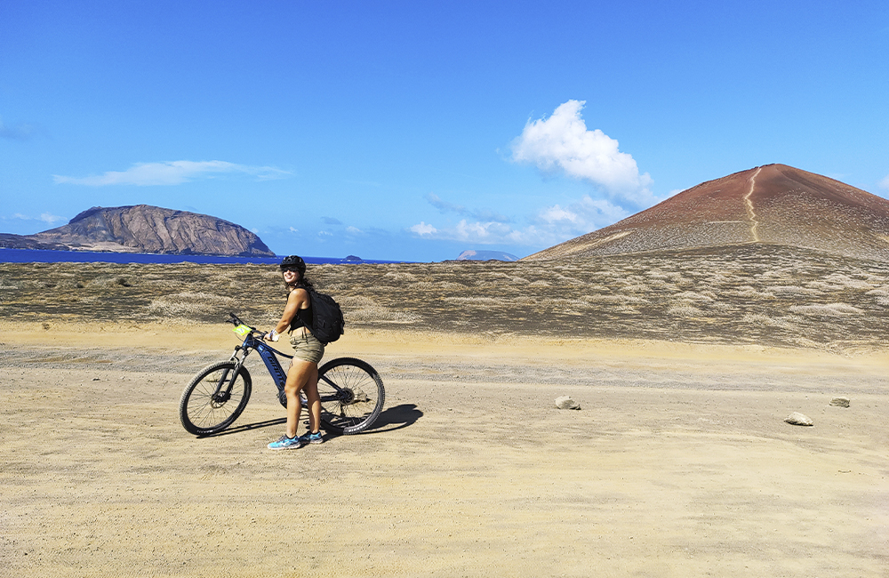 Cyclist in La Graciosa overlooking the island of Alegranza and Red Mountain